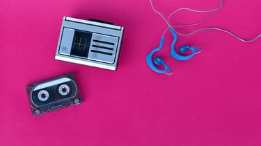 Walkman und Kopfhörer auf pinkem Hintergrund. Retro-Trends, Filmklassiker oder Kulthits lassen uns in Erinnerungen schwelgen. Warum sind wir nostalgisch, welche positiven Effekte hat Nostalgie und was hat die Sehnsucht nach der Vergangenheit mit der Gegenwart zu tun? | Bild: colourbox.com