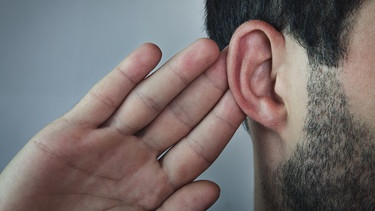 Mann hält sich eine Hand hinters Ohr. - Wer zuhören will, braucht Aufmerksamkeit und Empathie. Gutes Zuhören kann man aber auch lernen, etwa mit Techniken von Carl Rogers. Warum sich das lohnt. | Bild: colourbox.com